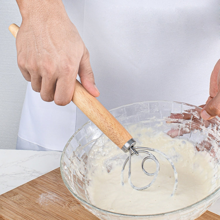 Hands using an oak-handled coil whisk to mix batter in a bowl