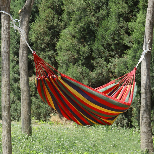 Red, yellow, and blue striped canvas hammock with fringed ends and hanging ropes