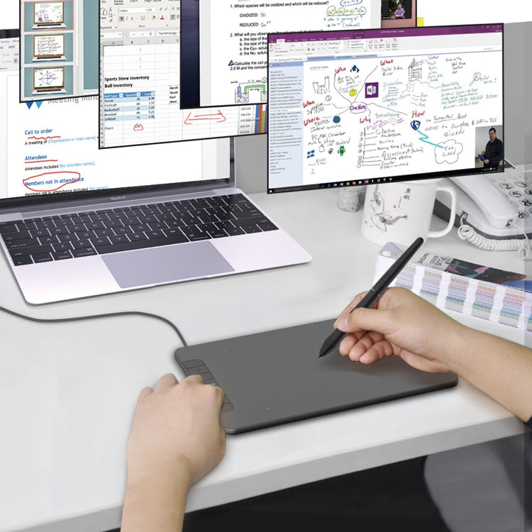 Digital drawing tablet with stylus in use at a laptop work setup