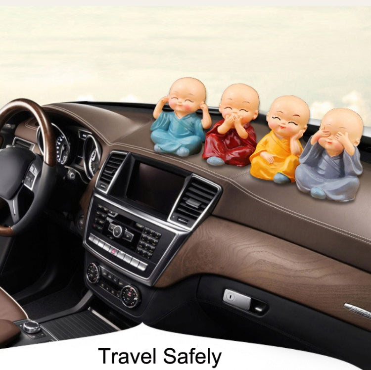 Car dashboard display of four seated monk ornaments in blue, dark brown, teal, and orange