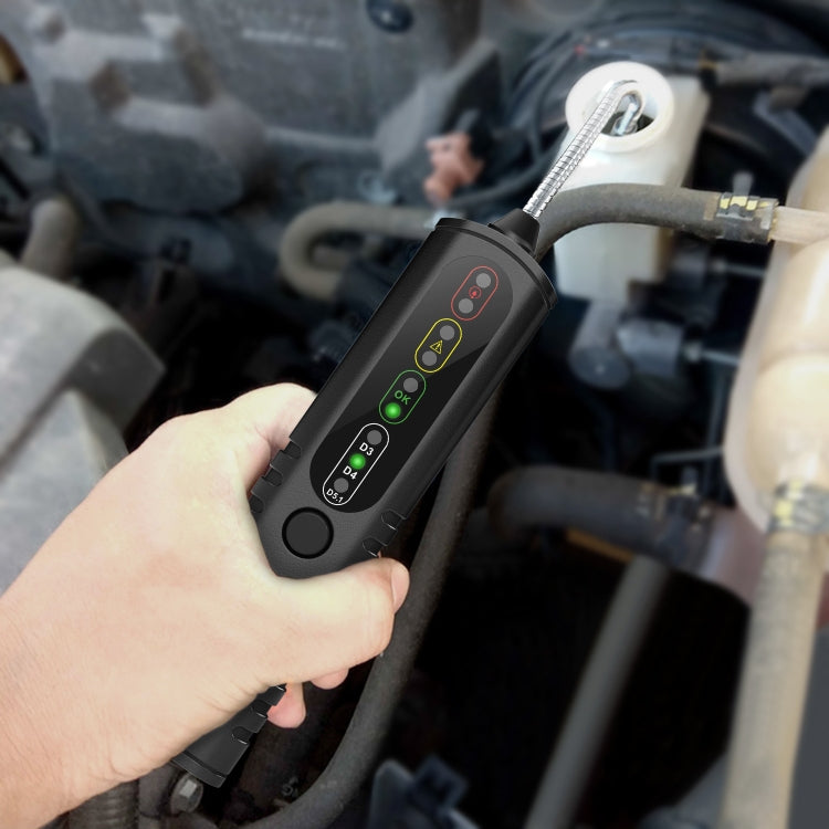 Brake fluid tester held in hand with flexible probe near engine hoses