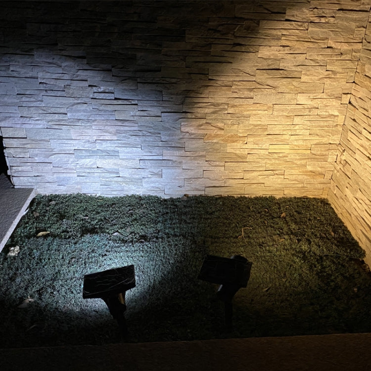 Solar flood light projecting white beam onto outdoor wall and garden ground