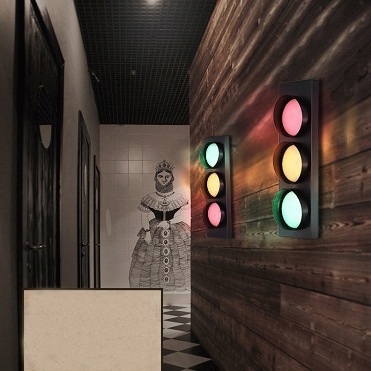 Wall-mounted traffic light sconce with glowing green, amber, and pink/red circular lenses