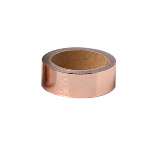 Rose gold metallic decorative tape roll with exposed adhesive backing and cardboard core