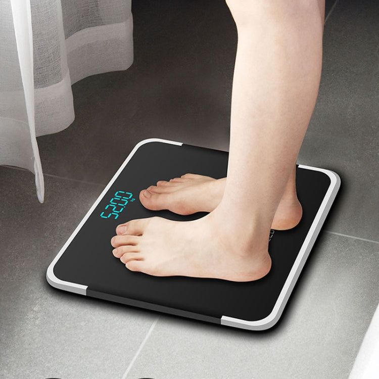 Bright black battery digital bathroom scale with LCD display under barefoot use.