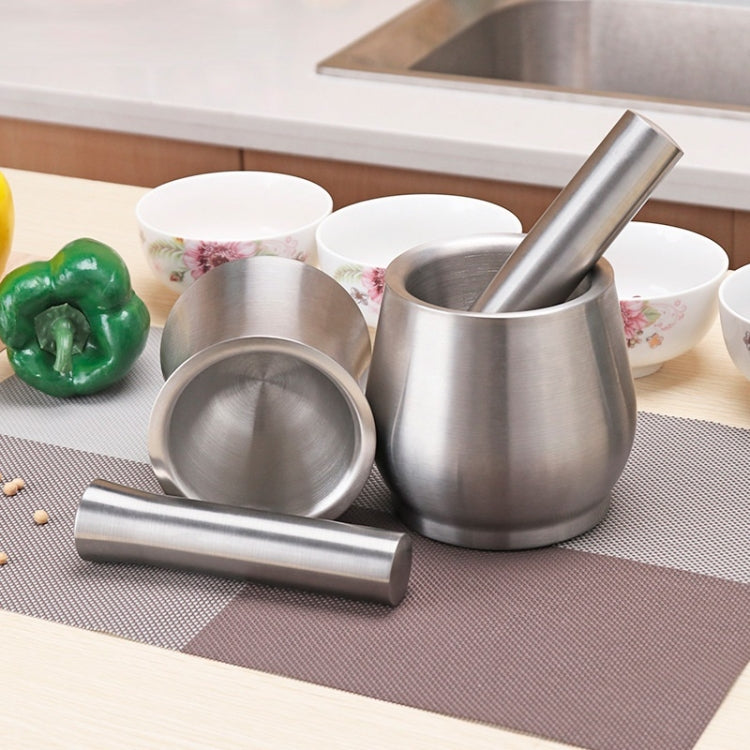 Stainless steel garlic masher with rod and bowl on countertop with ingredients