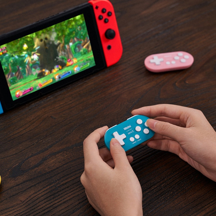 Blue wireless Bluetooth mini controller in hands beside gaming console
