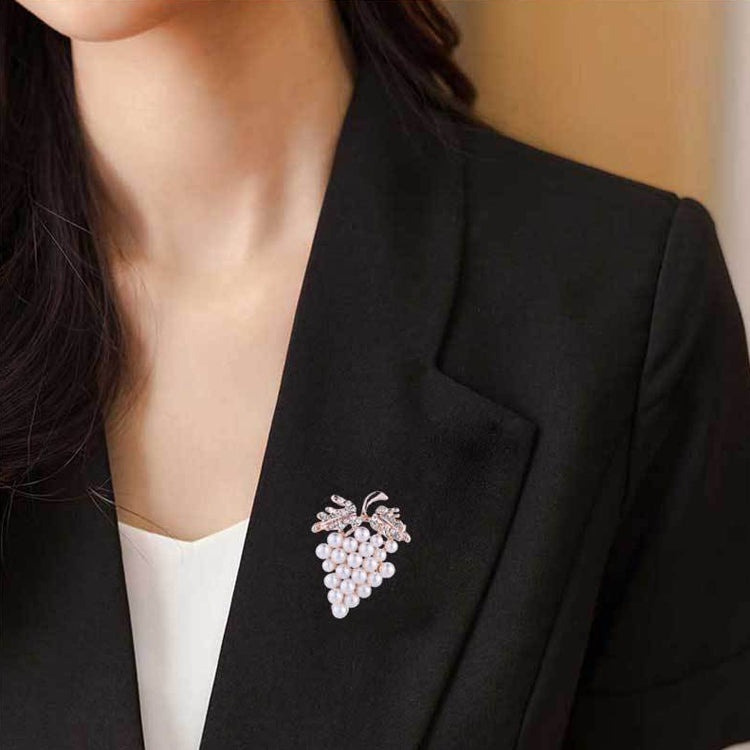 Grape-shaped pearl and rhinestone brooch on black blazer lapel