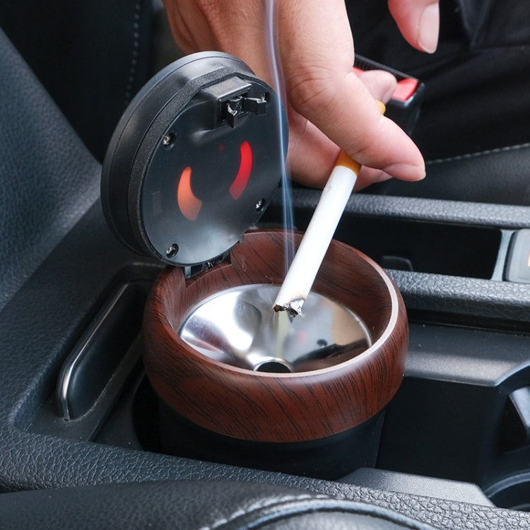 Car ashtray with open cover and wood-grain bowl, cigarette being placed