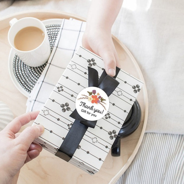 Hands applying a round Thank you sealing sticker to a gift envelope