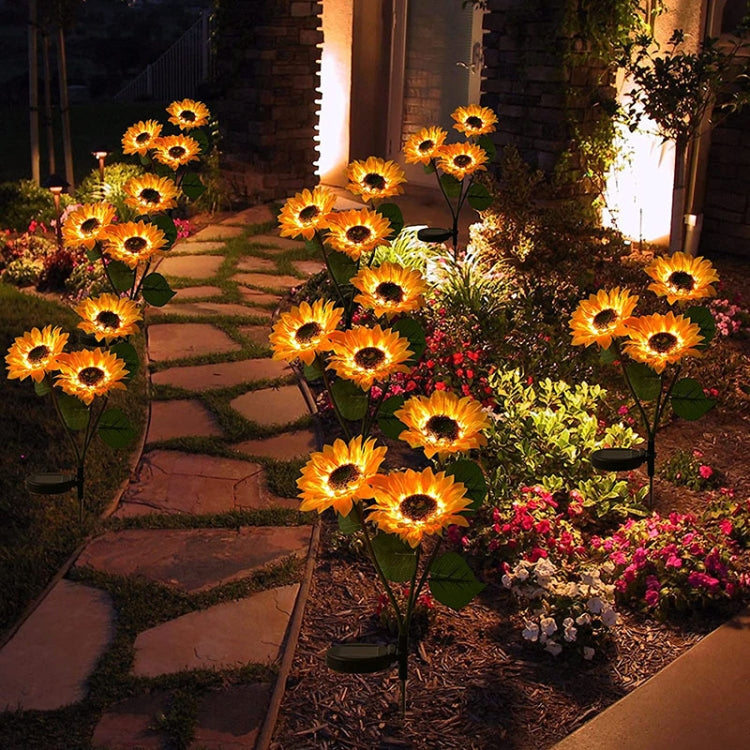 Solar sunflower garden stake lights with glowing yellow blooms along garden path at night.