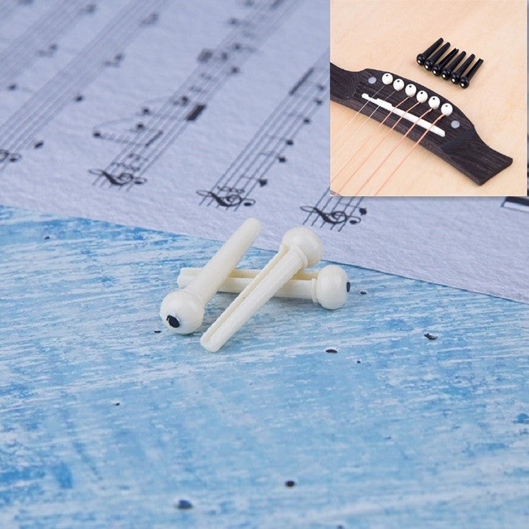 White guitar string nails with plastic conical heads, scattered on blue paper