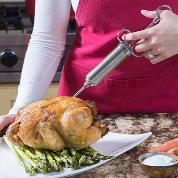 Stainless steel seasoning injector syringe injecting seasoning into roasted turkey on a platter