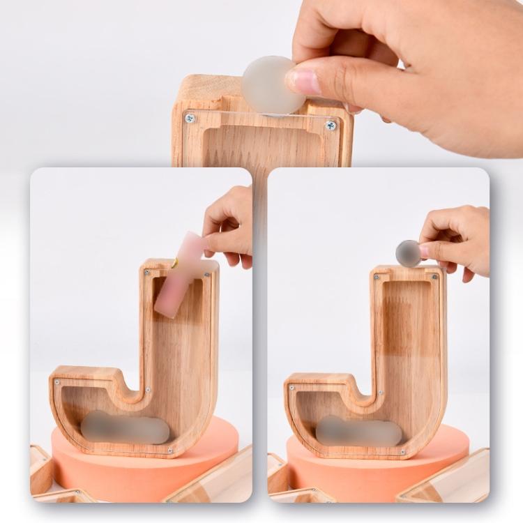 Wooden alphabet piggy bank letter with coin deposit slot, shown with hand inserting coin