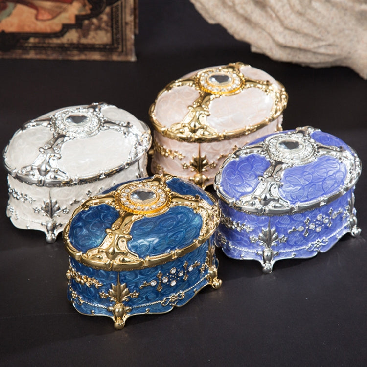 Oval metal jewelry storage boxes in silver, gold, and blue with diamond-style details
