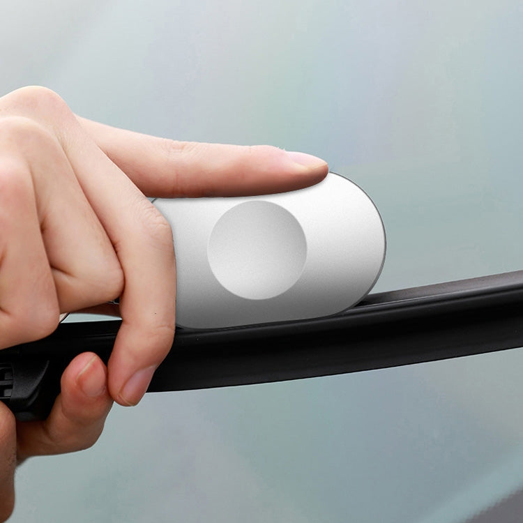 Hand holding silver portable rain scraper against car wiper blade