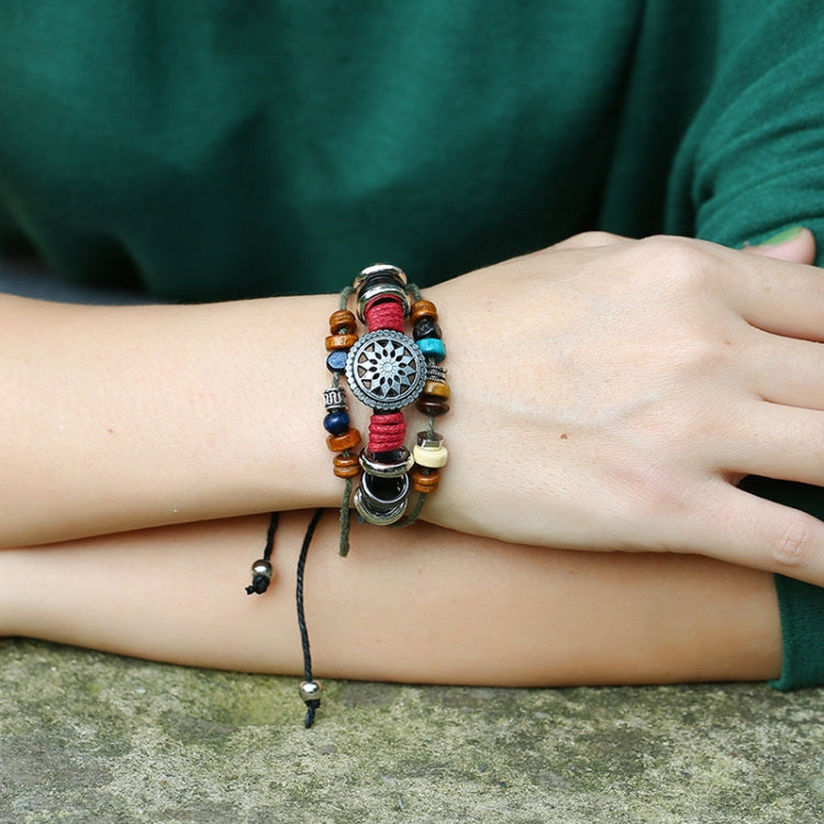 Beaded leather bracelet on wrist with circular silver charm, red and blue beads, metal rings