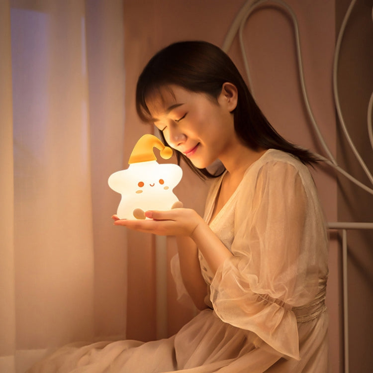 Glowing star-shaped silicone bedside night light held by a smiling child
