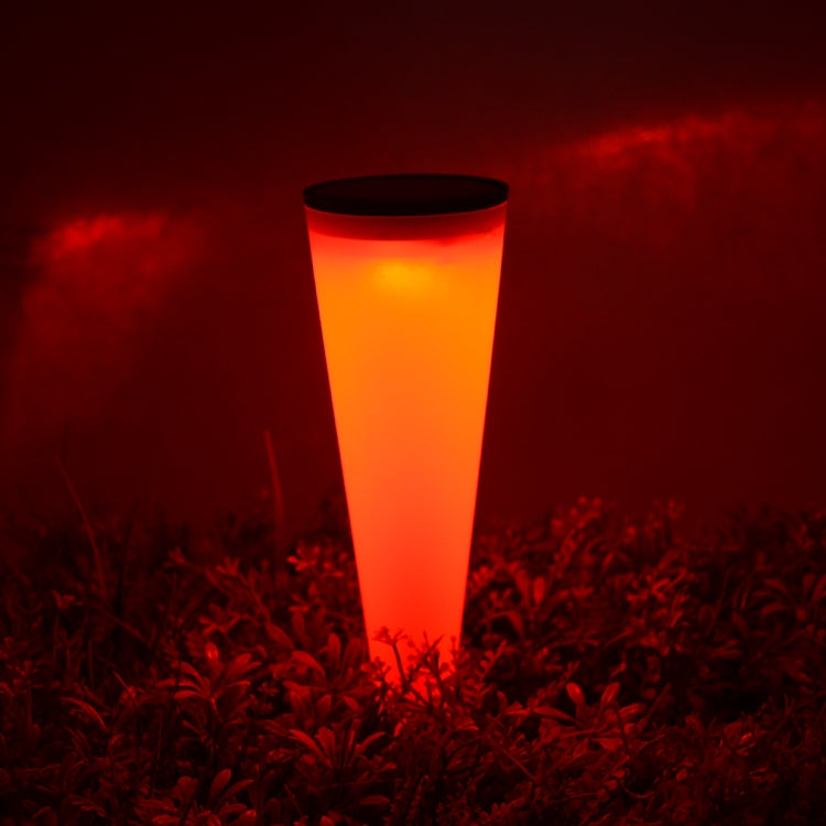 Outdoor solar wall lamp glowing red-orange cone light above garden plants.