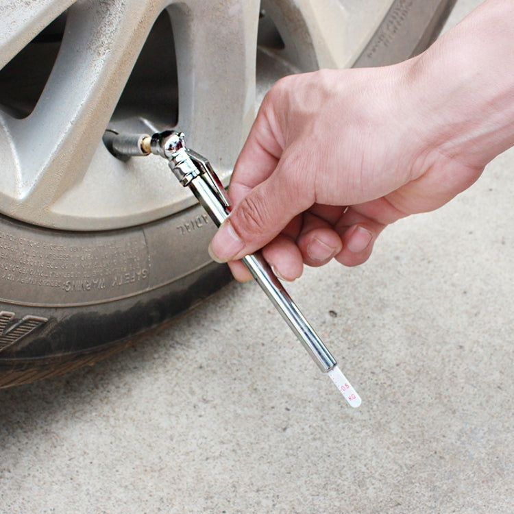 Hand using tire gauge pen on car wheel valve, silver metal tube