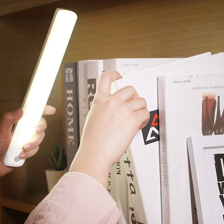 White induction LED cabinet light bar being installed by hand, magnetic rechargeable