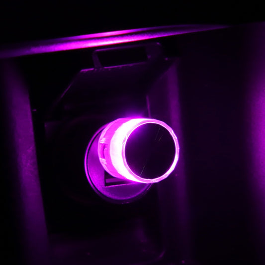 Car USB LED atmosphere lamp in round housing, lit purple on car console panel