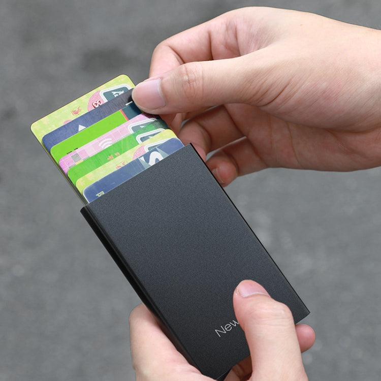 Hand holding a black RFID-protected metal card holder with cards inside