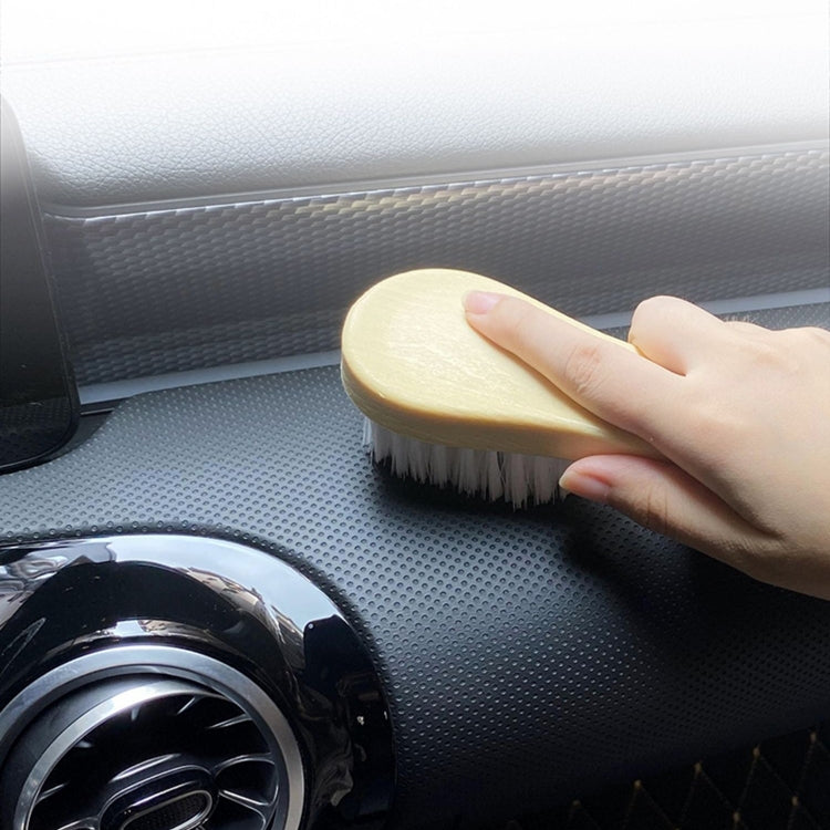Tan-handled soft bristle brush held against car interior for cleaning