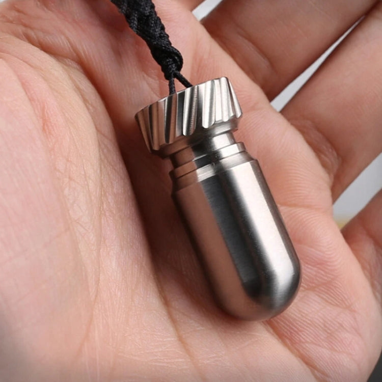 Titanium mini pill jar with ribbed cap held in hand, brushed silver color.