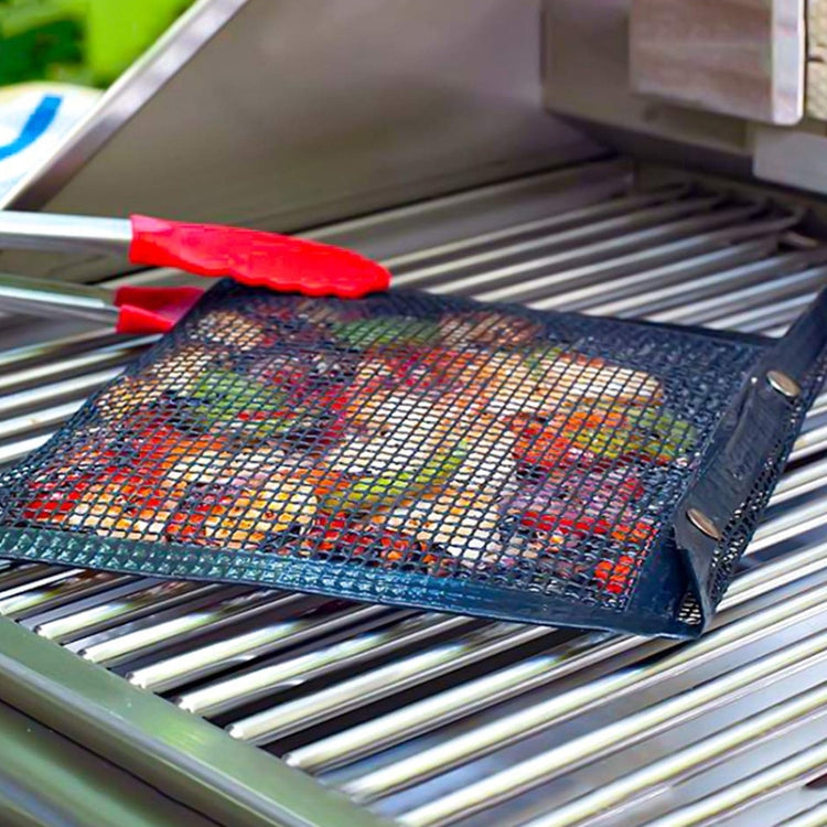 Black non-stick mesh grilling bag with handle resting on grill grates
