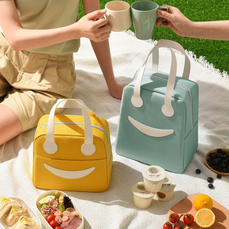 Yellow and mint lunch bags with leather handles and smile face, ready for carrying.
