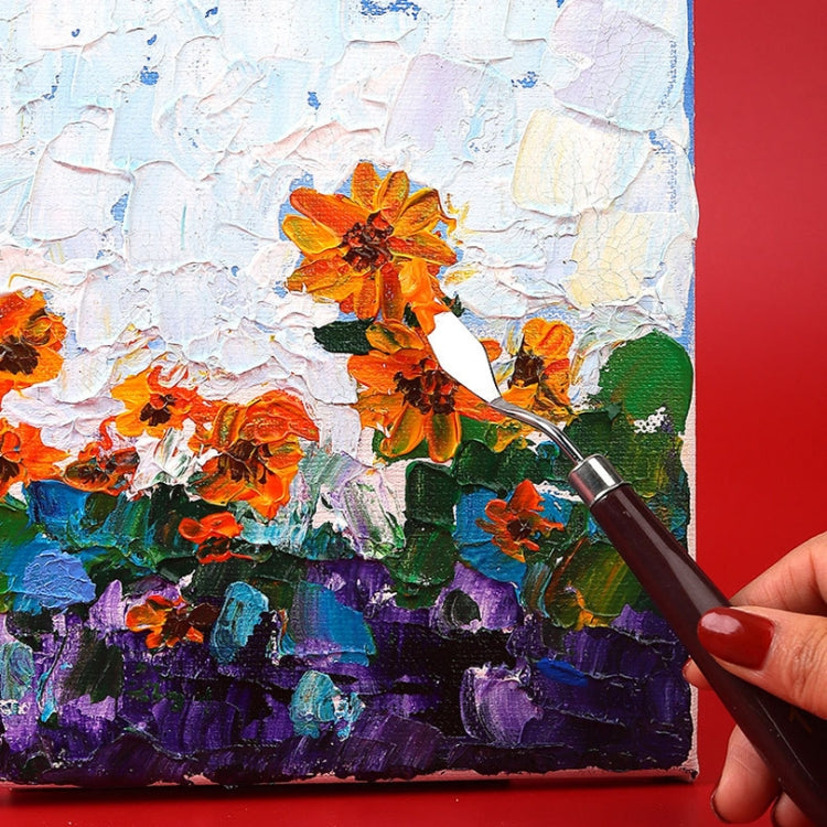 Paint knife applying color on canvas with dark handle and metal blade