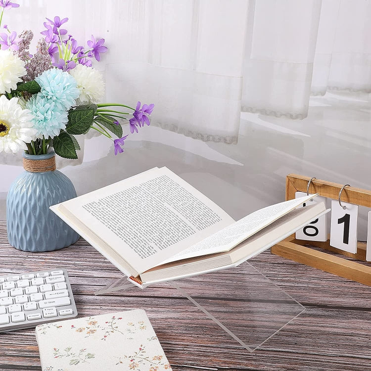 Clear X-shaped acrylic music or book display stand holding an open book