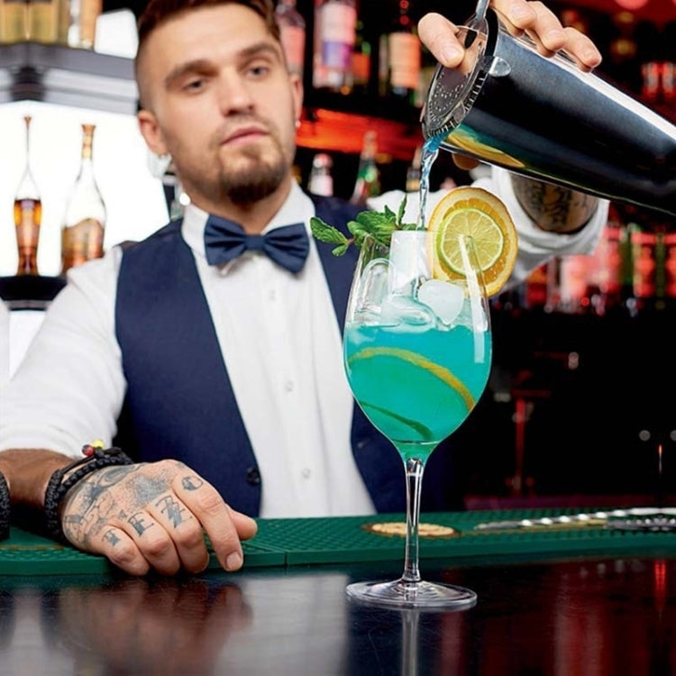 Stainless steel cocktail shaker being poured into a glass by a bartender
