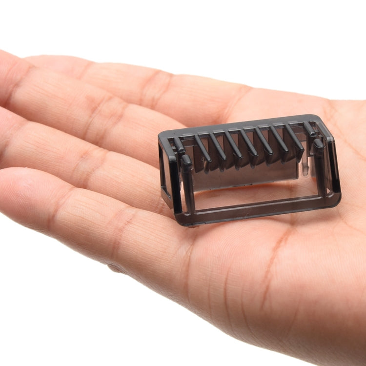 Black shaver positioning comb held in hand, with adjustable length teeth