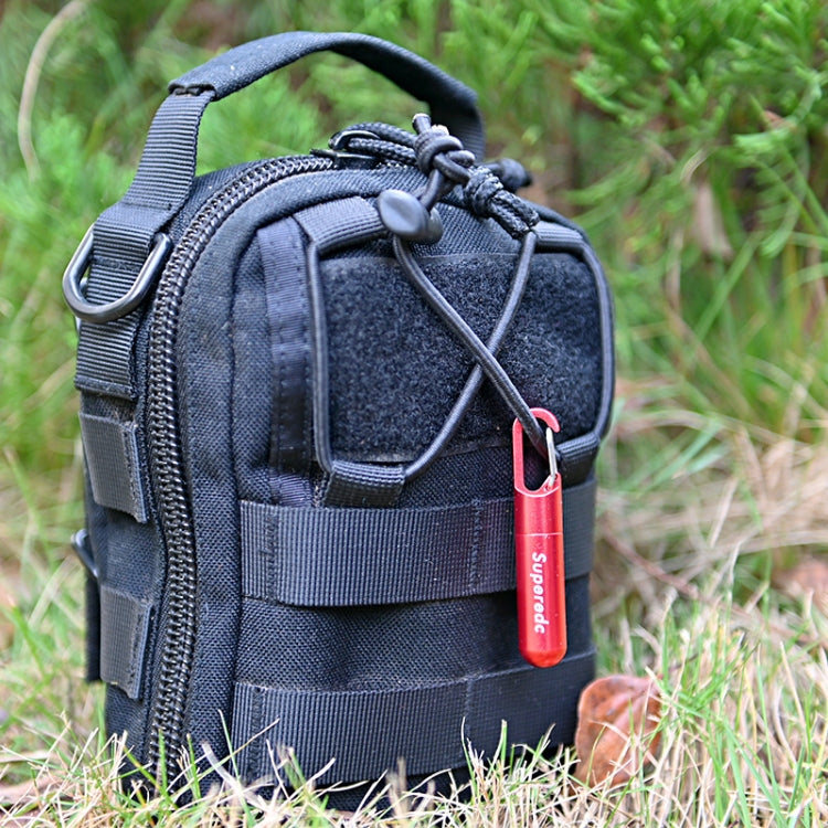 Red keychain knife pendant clipped to a black tactical pouch outdoors on grass
