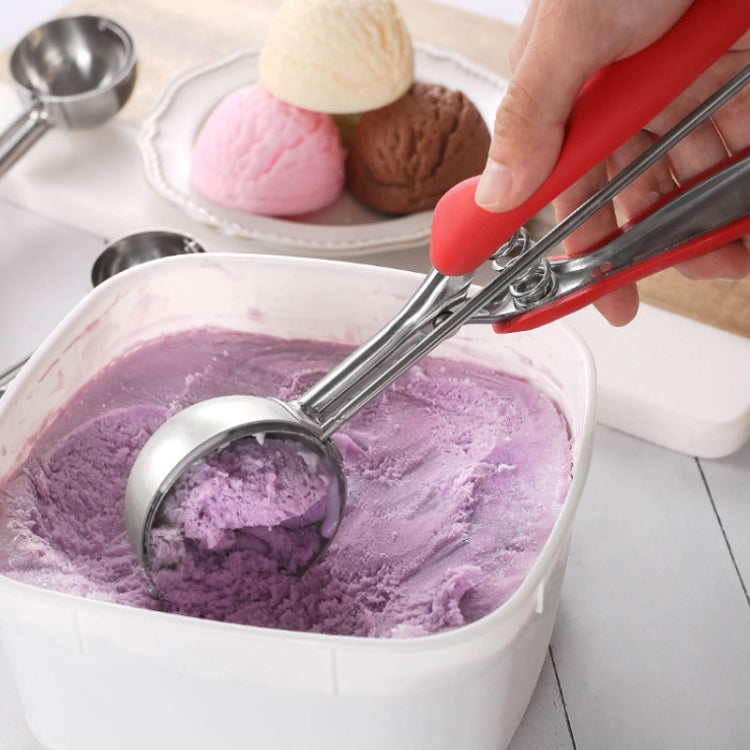Hand using stainless ice cream scoop with red silicone handle to serve purple ice cream