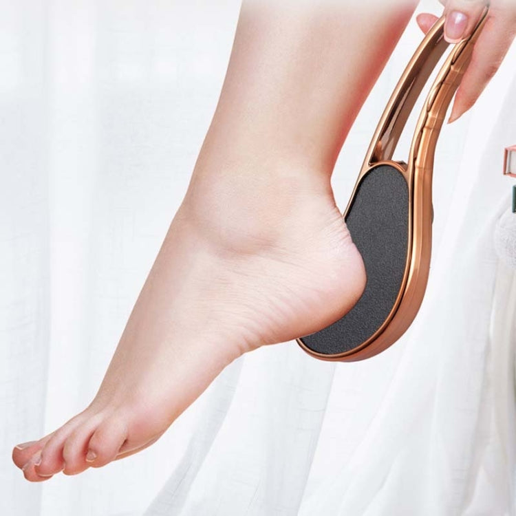 Exfoliating foot grinder used on a foot with rose-gold handle and dark textured heel pad