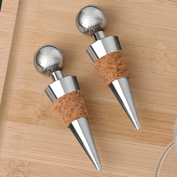 Metal wine bottle stoppers with cork inserts on wooden board, chrome heads