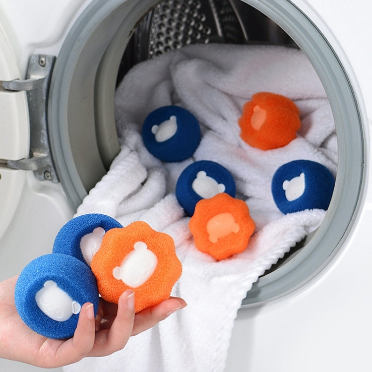 Laundry cleaning balls in washer drum: blue and orange bear shapes on towels.