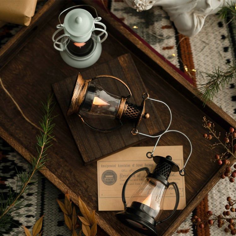 Black retro oil lantern ornament with clear glass body, arched handle, and lit wick flame