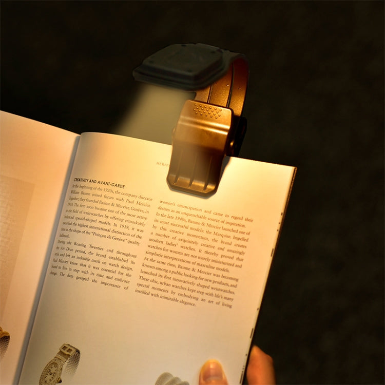 Book clip light attached to an open book, emitting warm reading light