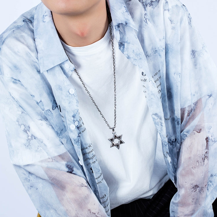 Six-point star pendant necklace worn on a man’s chest with a blue open shirt