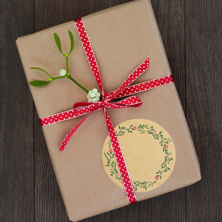 Kraft gift wrap with red polka-dot ribbon and round plant wreath sticker