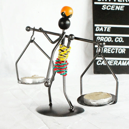 Man-shaped metal candlestick ornament with arms holding trays and colorful coiled body