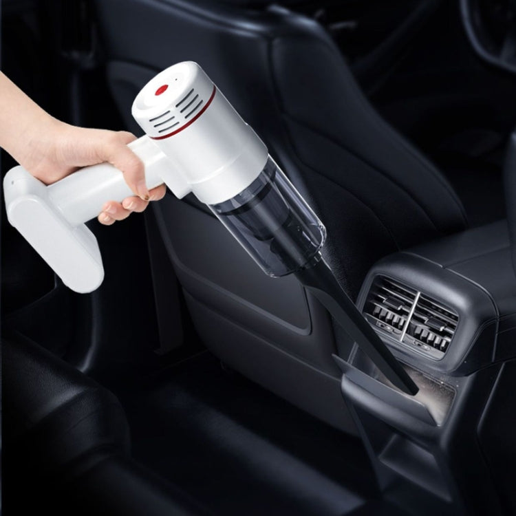 White handheld vacuum cleaner with brush nozzle, held while cleaning a car seat