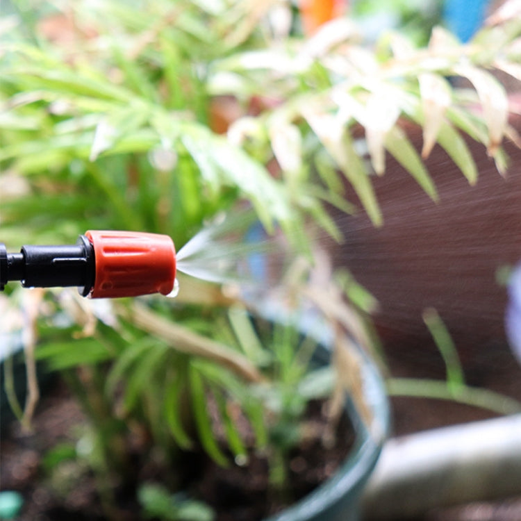 Orange drip irrigation spray head spraying water toward garden plants