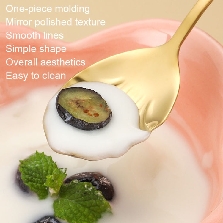 Gold shell-shaped spoon with glossy finish, stirring food in a white bowl