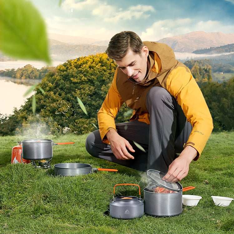 Camping cookware set being used on grass with pots and nested containers