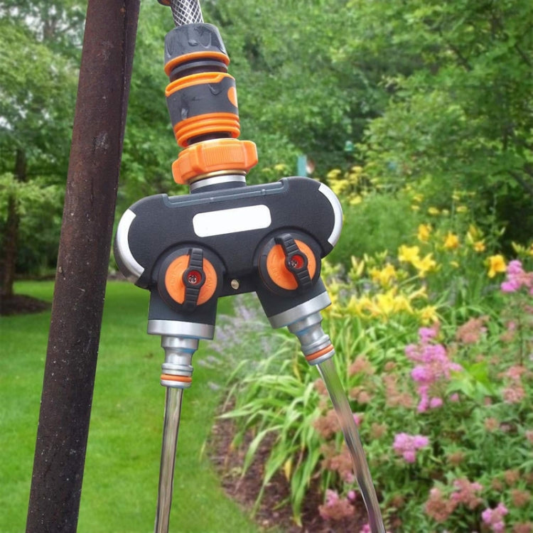 Two-outlet garden water divider valve attached to outdoor tap with twin hoses